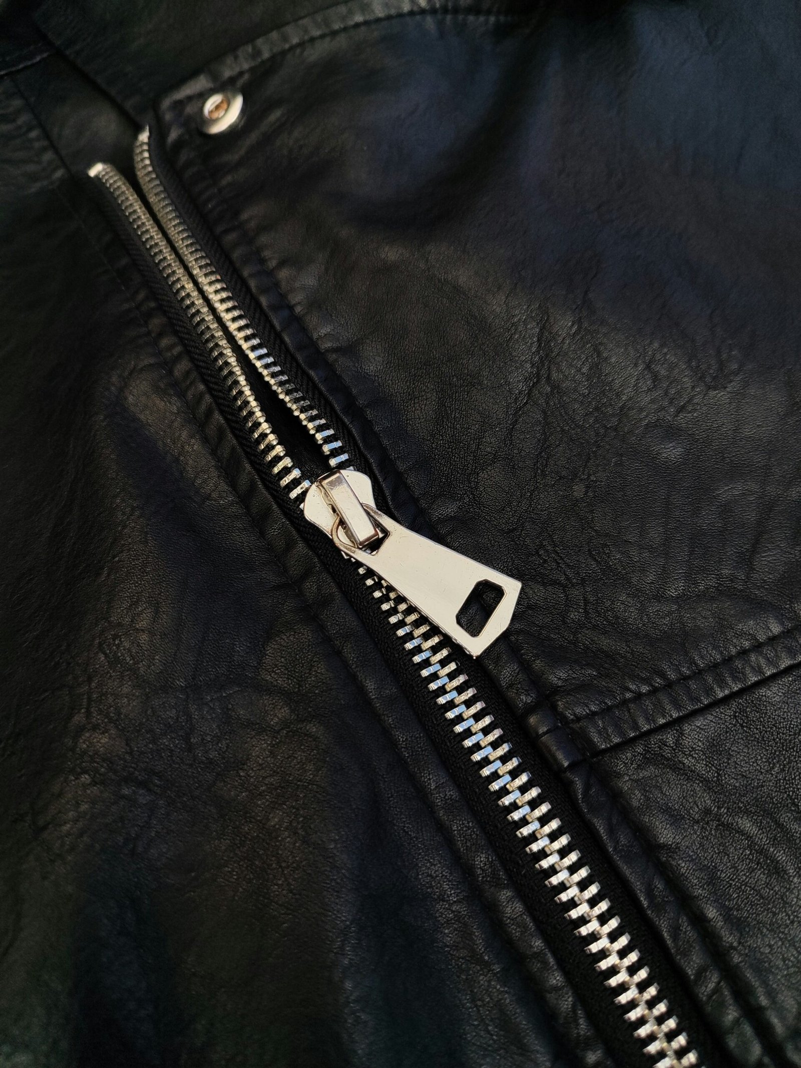 A close up of a black leather jacket with a zipper